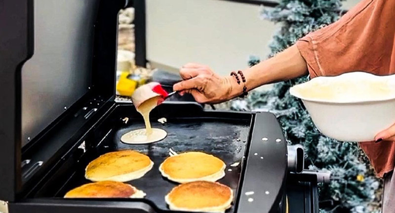 Person outdoors making pancakes on a countertop HALO griddle