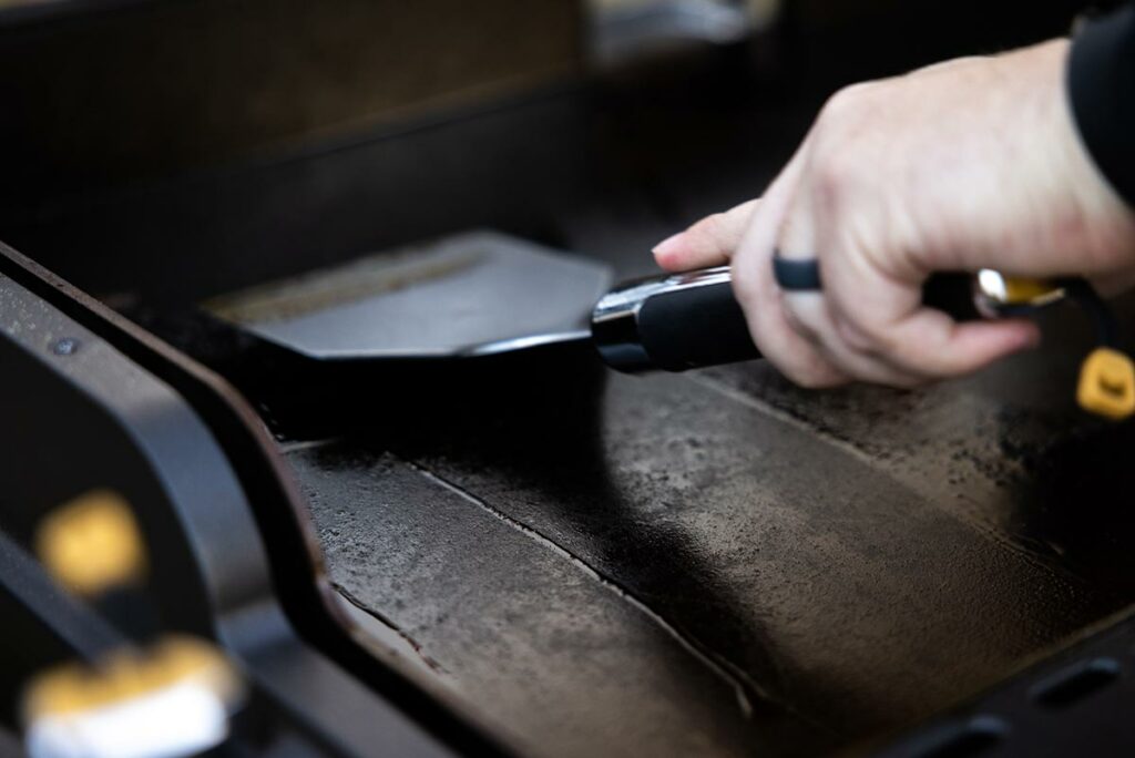 A person cleaning a griddle