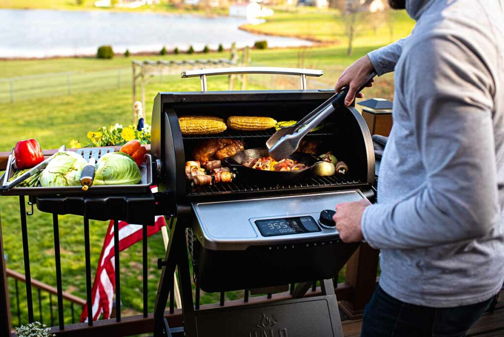 Man grilling various foods outside on a HALO outdoor grill