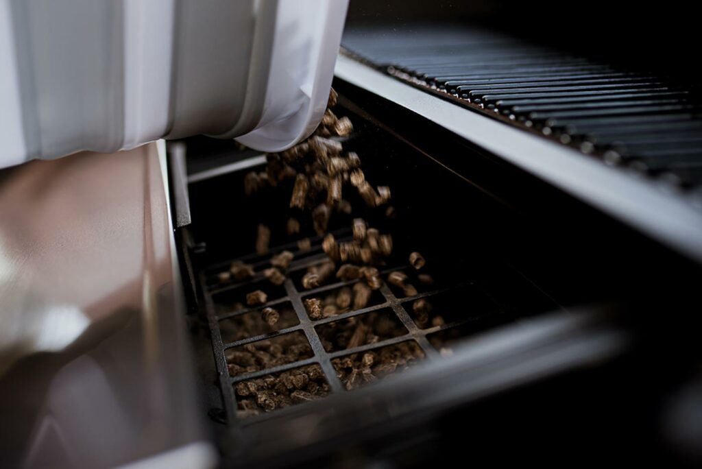 Wood pellets being added to a HALO Prime pellet grill hopper.