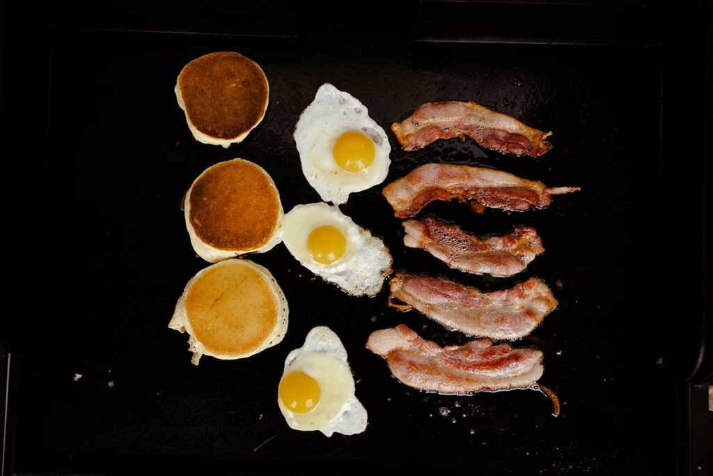Pancakes, eggs and bacon on a griddle
