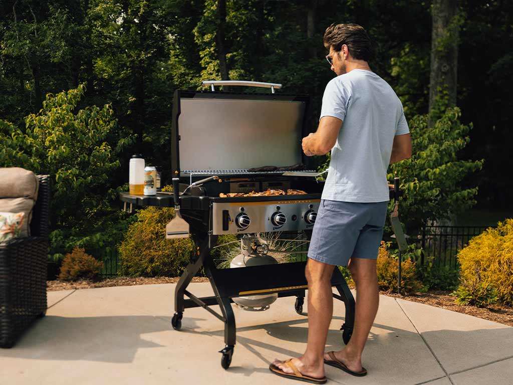 A man using a griddle outdoors.